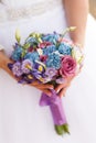 Wedding bouquet in pink and blue colors in the hands of the bride