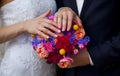 Wedding bouquet of pink roses, blue, red, yellow flowers and hands of bride and groom Royalty Free Stock Photo