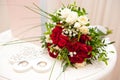 Wedding bouquet of red roses, white daisies and other flowers and wedding rings Royalty Free Stock Photo