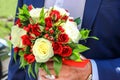 Wedding bouquet of red and white roses and hypericum in the hand of groom.