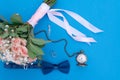 Wedding bouquet and wedding rings on a background of blue paper with a man`s butterfly and an old clock on a chain