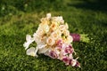 Wedding bouquet of roses and orchids lying on the lawn Royalty Free Stock Photo