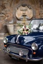 A wedding bouquet sitting on top of a vintage Morris Minor Rome Italy.