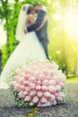 Wedding bouquet. Wedding bouquet lying on the ground in the park and in the background of a young couple in a romantic embrace Royalty Free Stock Photo