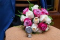 Wedding bouquet of white and pink red roses lying on a chair against a blue jacket Royalty Free Stock Photo