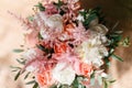 Wedding bouquet of white roses and buttercup on a wooden table. Lots of greenery, modern asymmetrical disheveled bridal