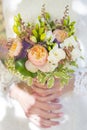 Wedding bouquet of white, violet and pink flowers in hands of bride