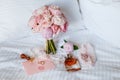 Wedding bride boutonniere, bouquet, perfume and garter laying on white bed linen. Pink bridal flowers and accessories Royalty Free Stock Photo