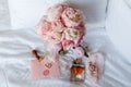 Wedding bride boutonniere, bouquet, perfume and garter laying on white bed linen. Pink bridal flowers and accessories Royalty Free Stock Photo