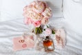 Wedding bride boutonniere, bouquet, perfume and garter laying on white bed linen. Pink bridal flowers and accessories Royalty Free Stock Photo