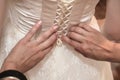 Wedding, bridesmaid helps to tie the corset on the wedding dress of the bride. Royalty Free Stock Photo