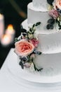 A wedding cake. Appetizing white cake four tiers on a beige table, decorated with roses, eucalyptus, on a light green background