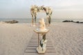 Wedding cake at a beach wedding on the background of a beautiful arch for an exit ceremony. Royalty Free Stock Photo