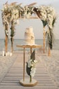 Wedding cake at a beach wedding on the background of a beautiful arch for an exit ceremony. Royalty Free Stock Photo