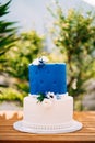 Wedding cake with beads and flowers stands on a wooden table Royalty Free Stock Photo