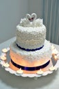 White wedding cake with cream decorated with swans and burning candles Royalty Free Stock Photo