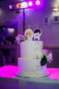 Wedding cake with figures of the bride and groom on a table in a restaurant, disco lights in the background Royalty Free Stock Photo