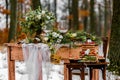 Wedding cake with fruit and an old wooden table with needles of cones and leaves during a wedding ceremony in winter on snow in