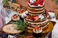 Wedding cake with fruit and an old wooden table with needles of cones and leaves during a wedding ceremony in winter on snow in