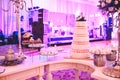 WEDDING CAKE AT IMPRESSIVE VIOLET VENUE WITH BEAUTIFUL CANDY TABLES, FLORAL GREEN DECORATION, BLURRED BACKGROUND, YELLOW LI Royalty Free Stock Photo