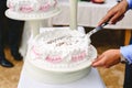 Wedding cake with meringue and cream cut with a large knife by a diner