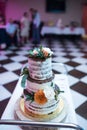 Wedding cake in rustic style. Three tiered chocolate wedding biscuit cake decorated with white and orange flowers. Royalty Free Stock Photo