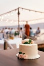 Wedding cake stands on a plate on the table against the backdrop of guests sitting at the table