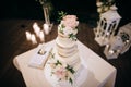 Wedding cake with white and pink flowers,  on the background of the wedding arch and candles Royalty Free Stock Photo