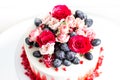 Wedding cake white and red colors decorated with roses and grapes sprinkled with powdered sugar Royalty Free Stock Photo