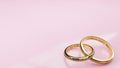 Wedding card All you need is love - pink background and two golden rings joined together forever with engraved words Royalty Free Stock Photo