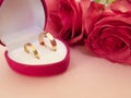 Wedding celebration with pink rose bouquet, gold wedding rings in the pink boxe, isolated on pink background. Concept of love and