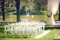 Wedding ceremony decoration with chairs and arch near the lake. Outdoor wedding ceremony at summer park