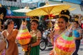 Wedding ceremony on the street. Young attractive women in traditional dresses and jewelery stand under umbrellas and hold bouquets