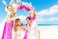 Wedding ceremony on a tropical beach in purple. Happy groom and Royalty Free Stock Photo