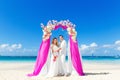 Wedding ceremony on a tropical beach in purple. Happy groom and Royalty Free Stock Photo