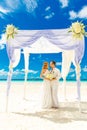 Wedding ceremony on a tropical beach in white. Happy groom and b