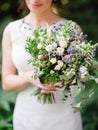 Wedding ceremony. Young bride holds oversized wedding bouquet with blue thistle flowers, jana roses, eucalyptus leaves Royalty Free Stock Photo