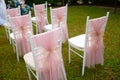 Wedding chairs decorated with pink ribbons on the green grass.wedding ceramony. Royalty Free Stock Photo