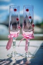 Wedding champagne glasses decorated with pink ribbons and flowers, close-up, vertical photo. Glasses for the bride and groom Royalty Free Stock Photo