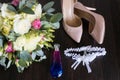 Wedding concept. Wedding accessories. Bridal beige shoes, perfume bottle, wedding garter and luxury bouquet