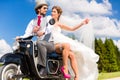 Bridal pair driving motor scooter wearing gown and suit Royalty Free Stock Photo