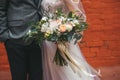 Wedding couple with bridal bouquet  is standing near a red brick wall Royalty Free Stock Photo