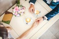 Wedding couple at cafe, top view. Man holds woman's hand, drinks espresso. Bride and groom coffee break dating gift Royalty Free Stock Photo