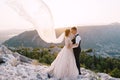 Fine-art destination wedding photo in Montenegro, Mount Lovchen. The wedding couple hugs on top of the mountain at