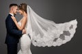 Wedding Couple Dancing. Romantic Bride and Groom Portrait. Bridal long Veil flying over Gray Studio Background Royalty Free Stock Photo