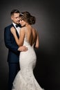 Wedding Couple Fashion Portrait. Bride Back view and Groom embracing Woman. Black Studio Background Royalty Free Stock Photo