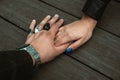 Wedding couple hold hands, his hand covers hers and their colorful rings stand out Royalty Free Stock Photo