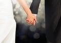 Wedding couple holding hands against glowing lights