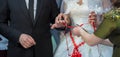 Wedding couple holding hands .Bride and groom hands with wedding flowers and bridal dress . Bride is wearing a ring on the hands