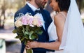 Wedding, couple and hug with flower bouquet outdoor at marriage celebration event for bride and groom. Happy interracial Royalty Free Stock Photo